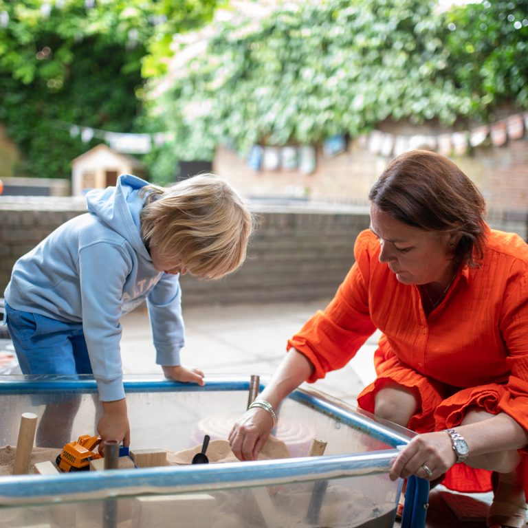 child and teacher in the sand pit