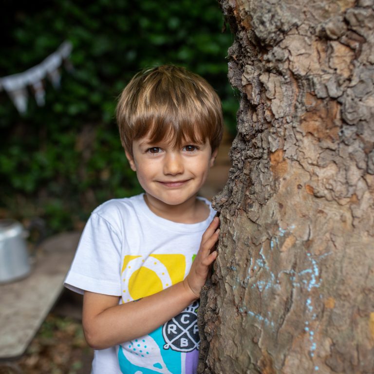 child holding onto tree