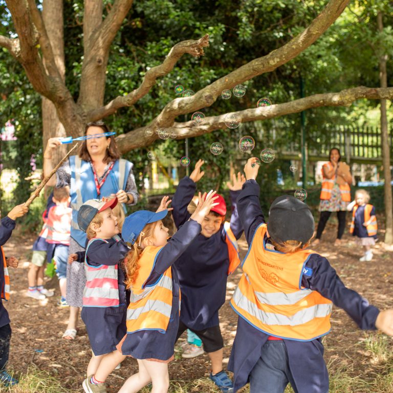 children all reaching out to catch bubbles