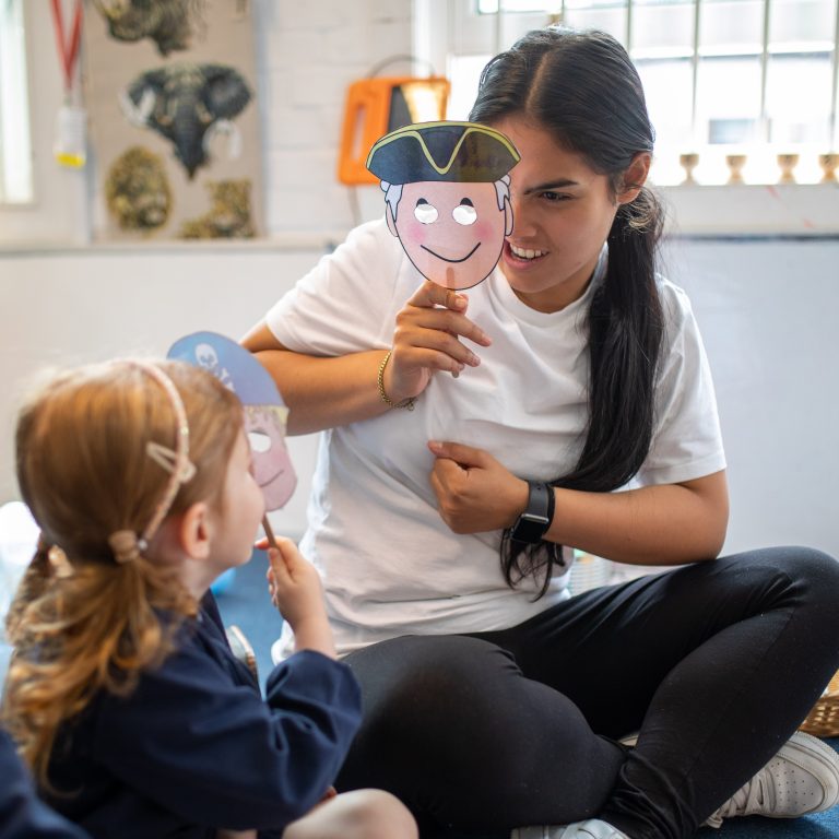 teacher and pupil holding masks up