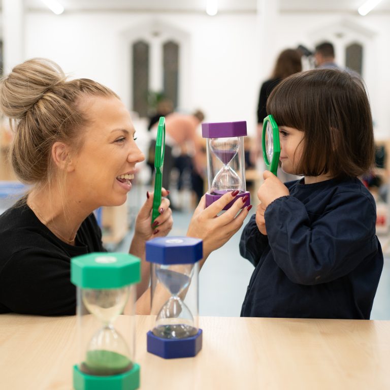 Girl using a magnifying glass with her teacher