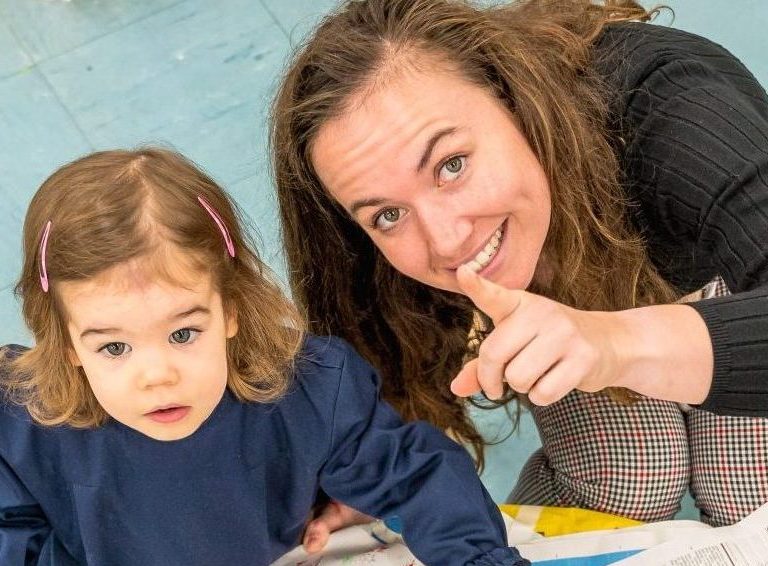 a teacher points upwards as the child looks up