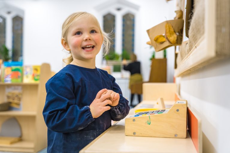 child looking up at her wooden cash register