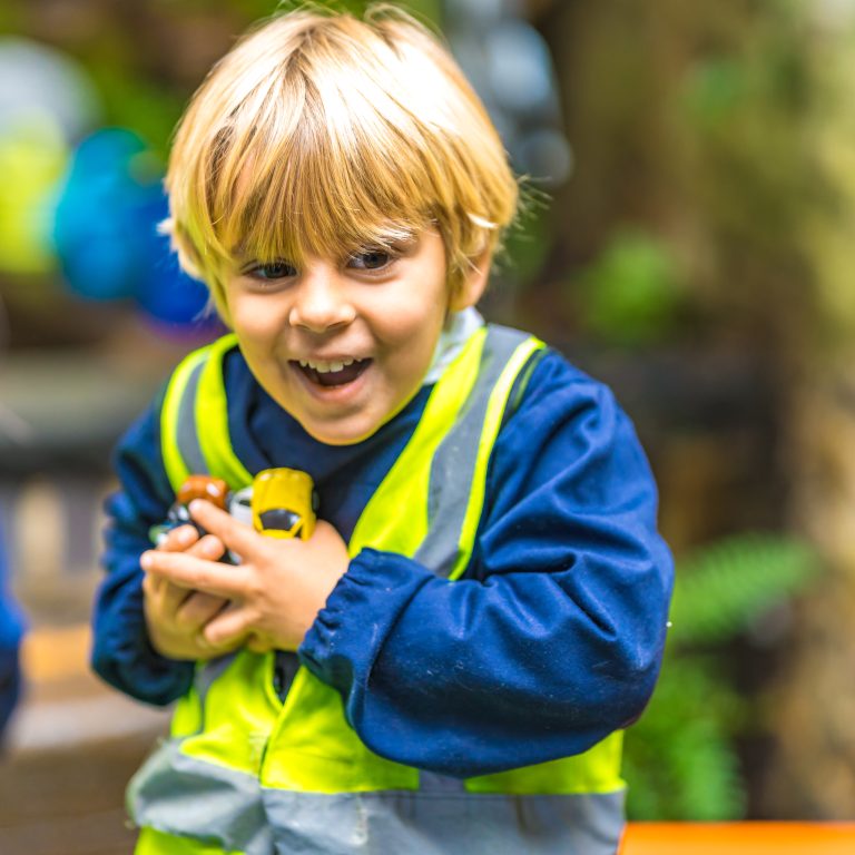 a child holding a bunch of toy cars in his hands